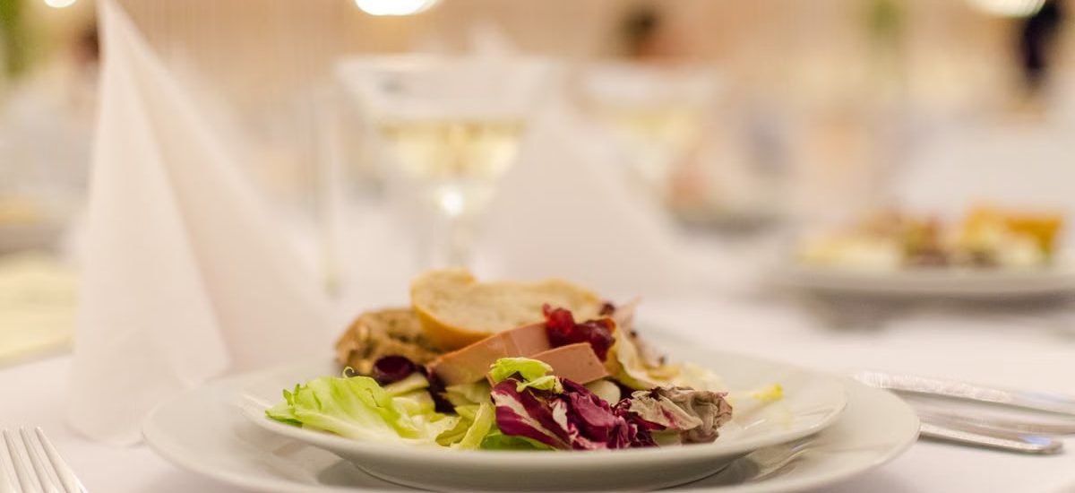 Plate of gourmet salad with bread on a elegantly set restaurant table, perfect for upscale dining experiences.