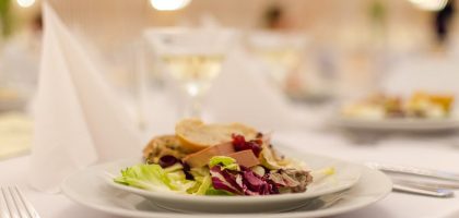 Plate of gourmet salad with bread on a elegantly set restaurant table, perfect for upscale dining experiences.